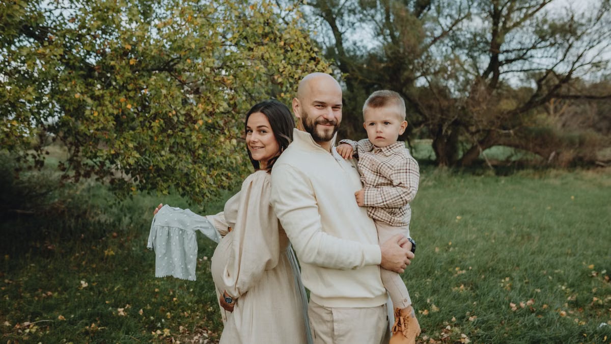 Young family enjoying time outdoors with their son, celebrating family moments in a lush green park during autumn.